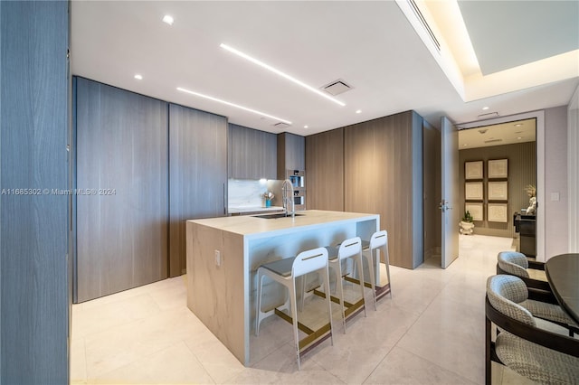 kitchen featuring a kitchen breakfast bar, a kitchen island with sink, and sink