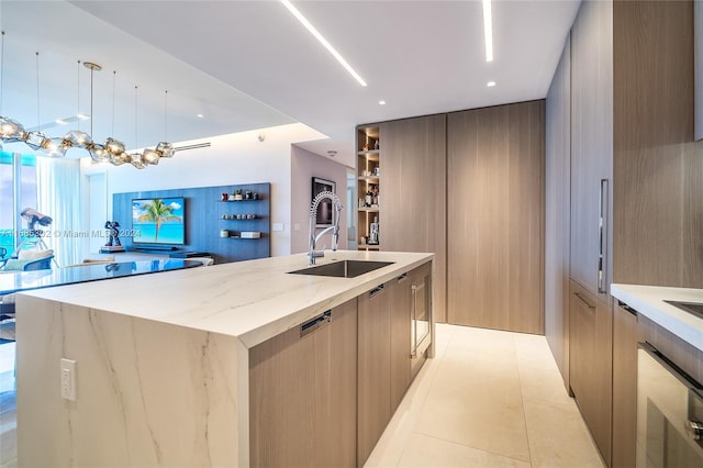 kitchen with a large island, light brown cabinets, light tile patterned floors, light stone countertops, and sink