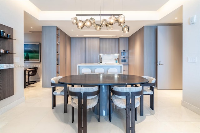 tiled dining area with a notable chandelier and a raised ceiling