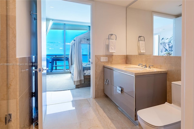 bathroom with vanity, toilet, and tile walls