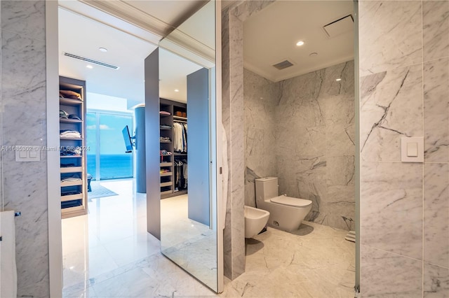 bathroom with tile walls, a bidet, and toilet