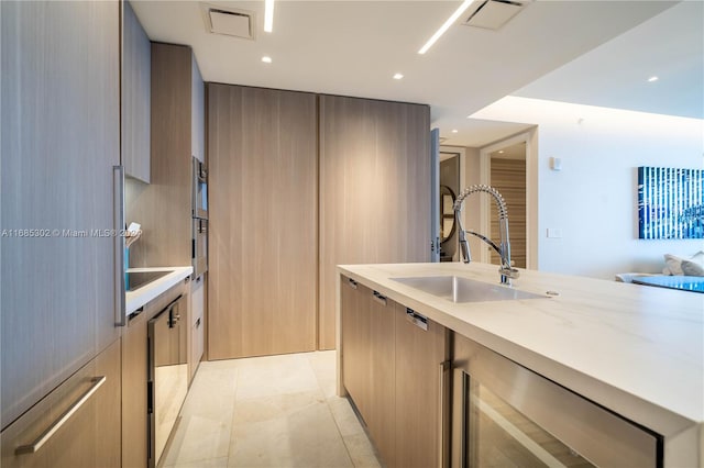 kitchen with light brown cabinets, light stone countertops, sink, and light tile patterned floors