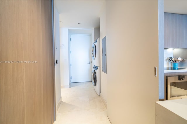 corridor with stacked washer / dryer and light tile patterned flooring