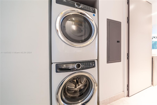 laundry area with electric panel and stacked washer and dryer