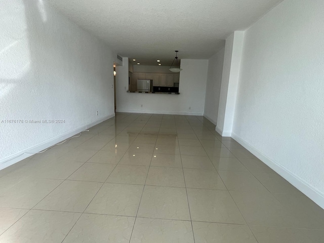 unfurnished living room with a textured ceiling and light tile patterned flooring