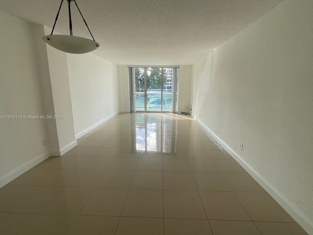 unfurnished room with a textured ceiling and light tile patterned floors