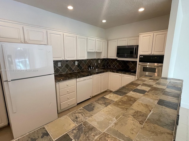 kitchen with decorative backsplash, a textured ceiling, white cabinetry, sink, and white appliances