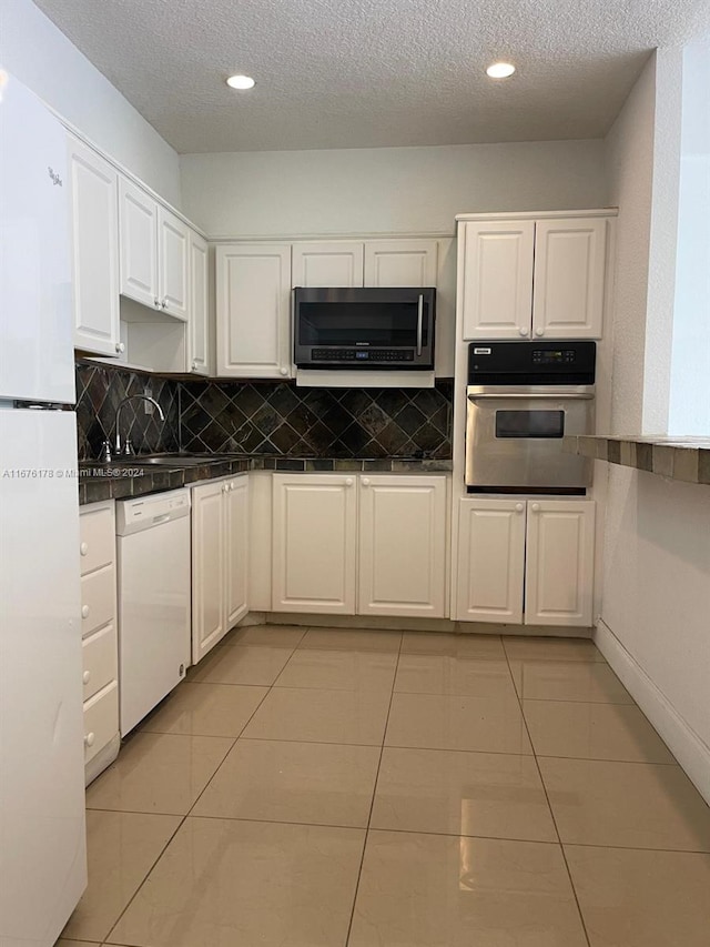 kitchen with stainless steel appliances, light tile patterned flooring, and white cabinets