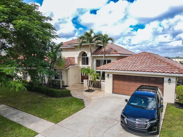 mediterranean / spanish house with a garage and a front lawn