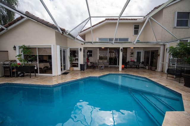 view of pool with glass enclosure, ceiling fan, and a patio area