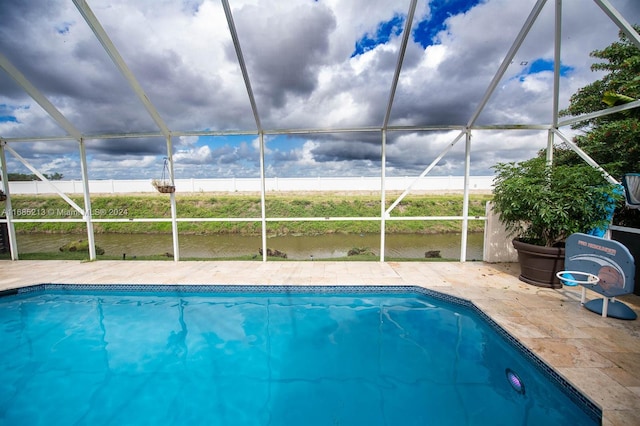 view of swimming pool with a patio, a water view, and a lanai