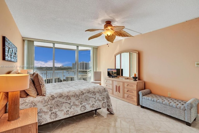 bedroom featuring expansive windows, a textured ceiling, access to exterior, and ceiling fan