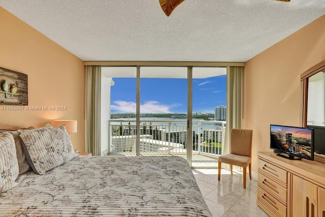 tiled bedroom with a textured ceiling, access to outside, and floor to ceiling windows