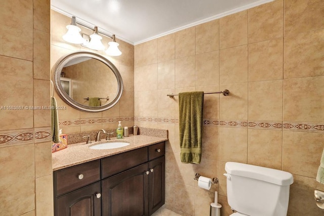 bathroom featuring vanity, tile walls, ornamental molding, and toilet