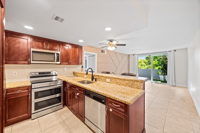 kitchen with light stone countertops, kitchen peninsula, sink, and appliances with stainless steel finishes