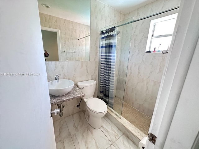 bathroom with curtained shower, sink, tile walls, and toilet