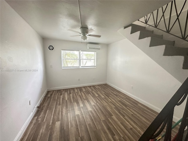 unfurnished room with a wall unit AC, dark hardwood / wood-style floors, and ceiling fan