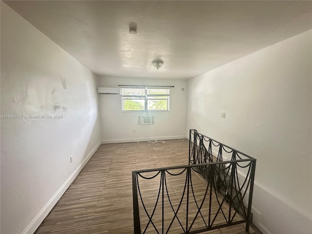 spare room featuring wood-type flooring and a wall mounted air conditioner