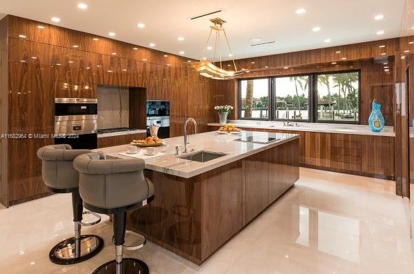 kitchen featuring a large island, a kitchen bar, wood walls, pendant lighting, and sink