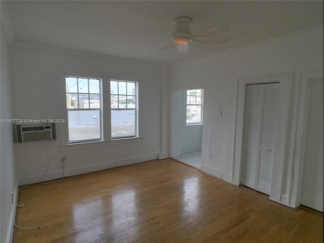 spare room featuring ceiling fan, cooling unit, and light wood-type flooring