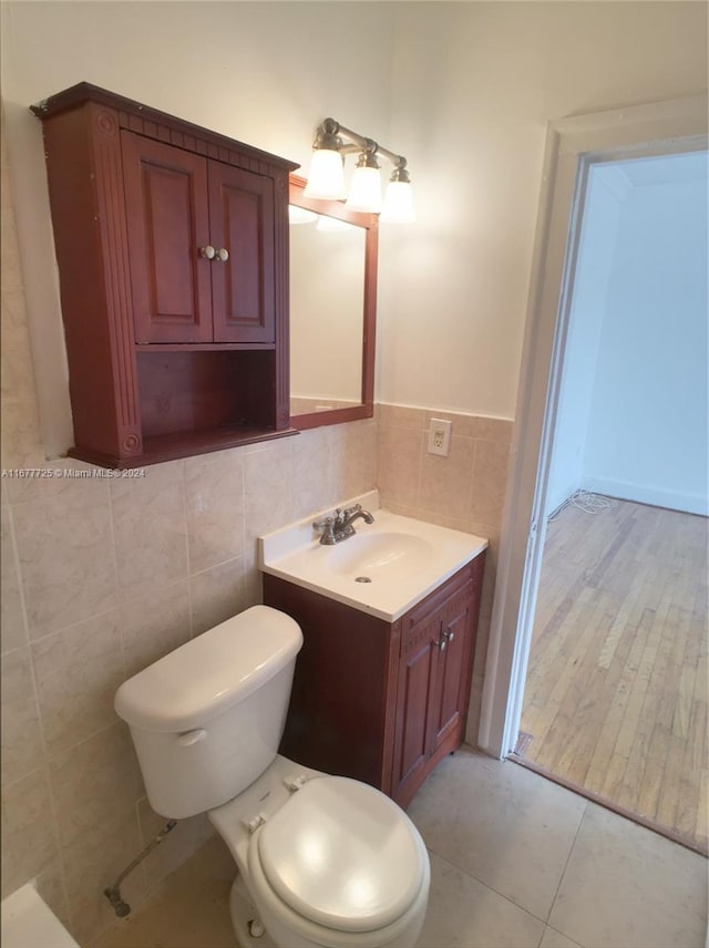 bathroom with tile walls, vanity, hardwood / wood-style flooring, and toilet