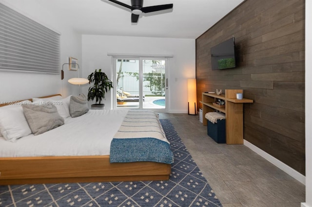 bedroom with ceiling fan, wooden walls, and access to outside