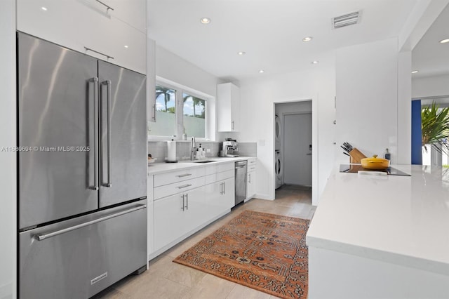 kitchen with washer / dryer, visible vents, white cabinetry, light countertops, and appliances with stainless steel finishes