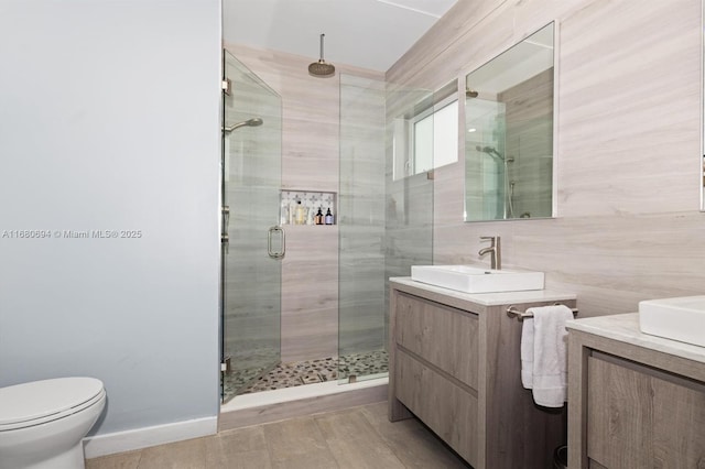 bathroom with vanity, toilet, tile walls, and walk in shower