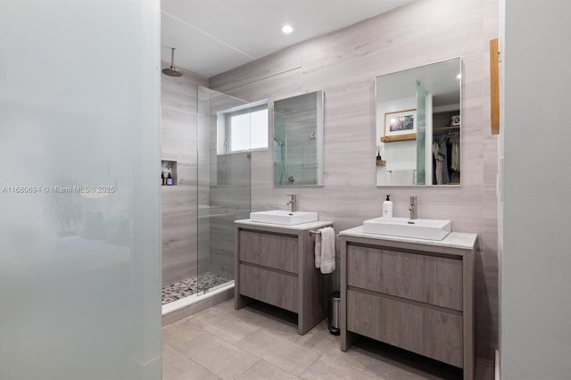 bathroom featuring tile patterned flooring, vanity, a tile shower, and tile walls