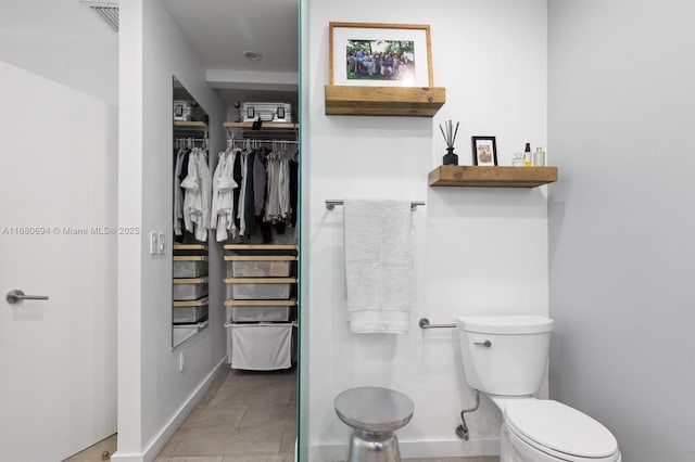 bathroom with toilet, visible vents, a spacious closet, and baseboards