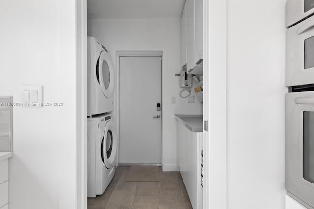 laundry area with light tile patterned floors and stacked washing maching and dryer