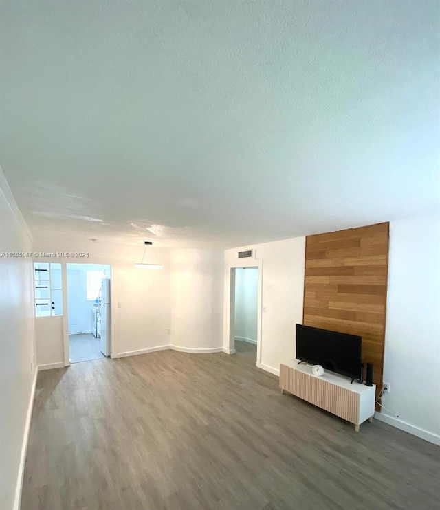 unfurnished living room with wood walls and wood-type flooring