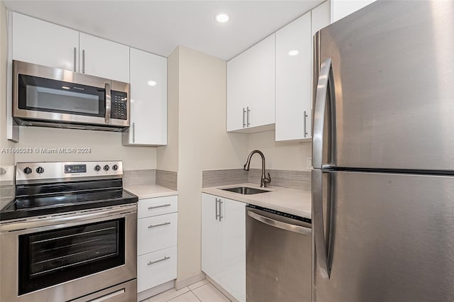 kitchen with light tile patterned flooring, white cabinets, stainless steel appliances, and sink