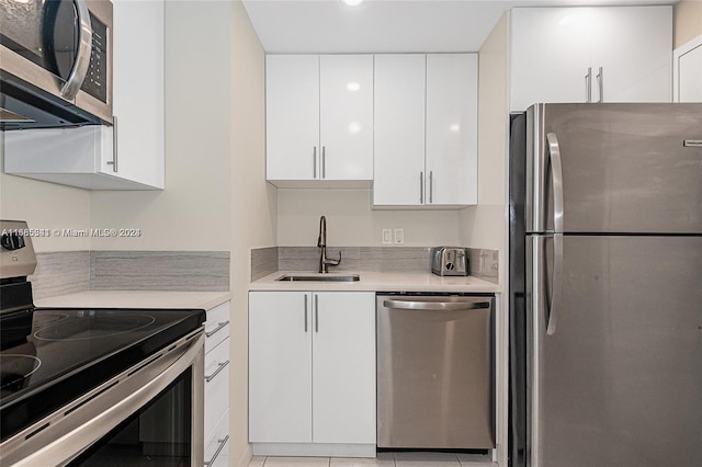 kitchen with light tile patterned floors, appliances with stainless steel finishes, sink, and white cabinets