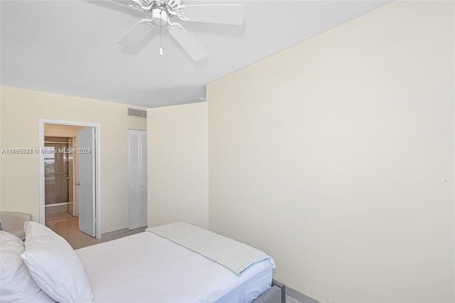 tiled bedroom featuring connected bathroom and ceiling fan