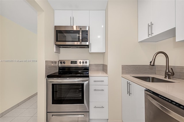 kitchen featuring white cabinetry, stainless steel appliances, sink, and light tile patterned floors