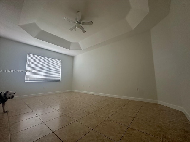 tiled spare room featuring ceiling fan and a raised ceiling