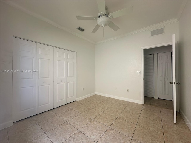 unfurnished bedroom with light tile patterned flooring, ceiling fan, crown molding, and a closet