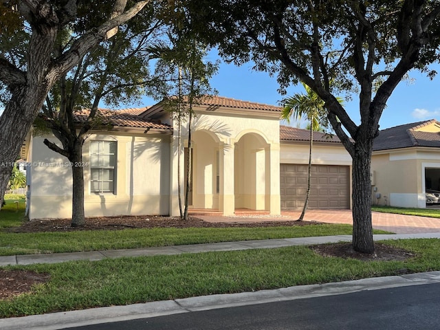 mediterranean / spanish-style home with a garage and a front lawn