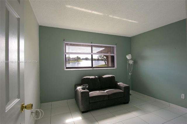 living area featuring a textured ceiling, light tile patterned flooring, and a water view