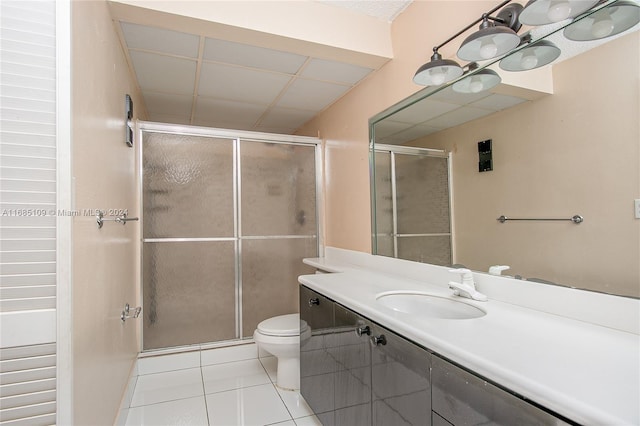 bathroom with vanity, toilet, tile patterned flooring, and a shower with door