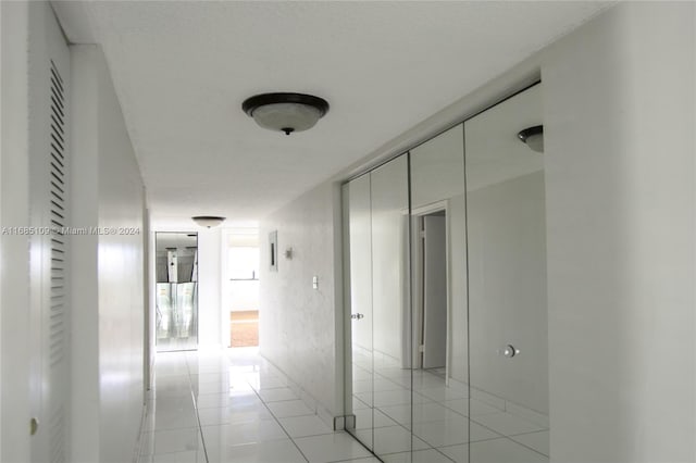 hallway featuring a textured ceiling and light tile patterned flooring