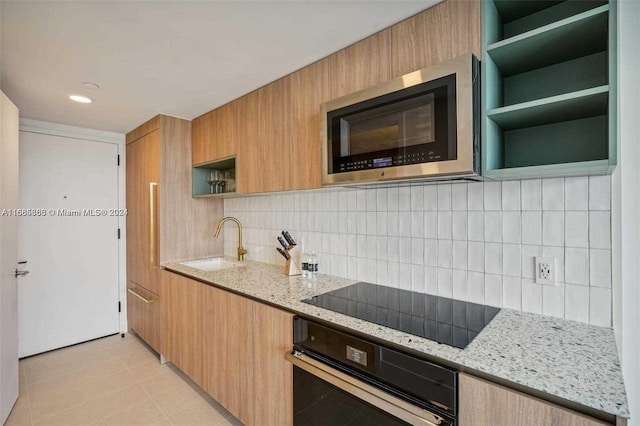 kitchen with tasteful backsplash, black appliances, sink, and light stone counters