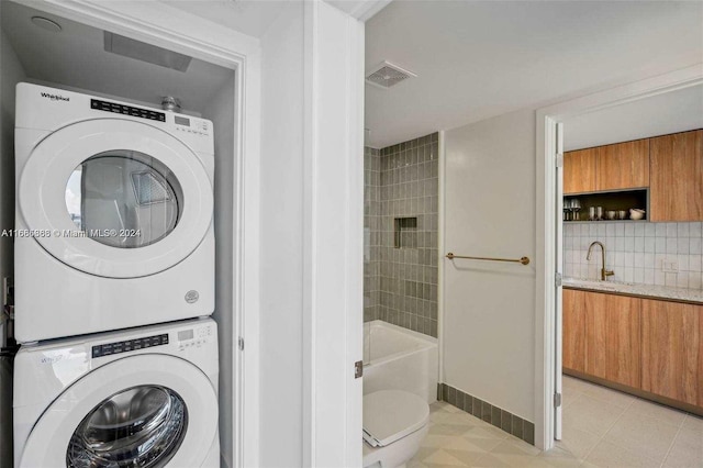 clothes washing area featuring stacked washer / drying machine, sink, and light tile patterned floors