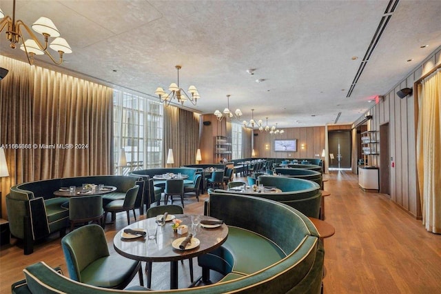 dining room with hardwood / wood-style floors, a textured ceiling, and wooden walls