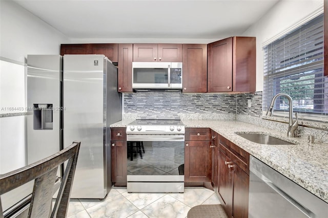 kitchen featuring tasteful backsplash, stainless steel appliances, sink, and light stone counters