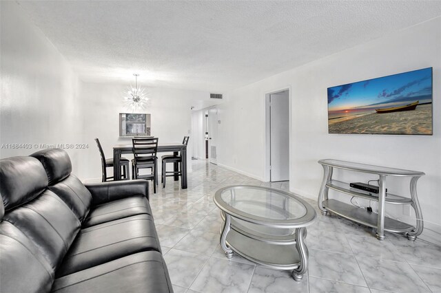 9540 Sunrise Lakes Blvd Unit 103, Sunrise, FL 33322 - living area with light marble finish flooring, a textured ceiling, a chandelier, and baseboards
