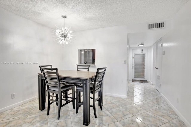 dining area featuring a notable chandelier and a textured ceiling