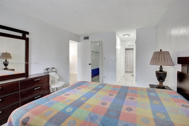 bedroom with a spacious closet, a textured ceiling, and a closet