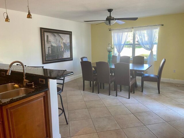 tiled dining space featuring ceiling fan and sink